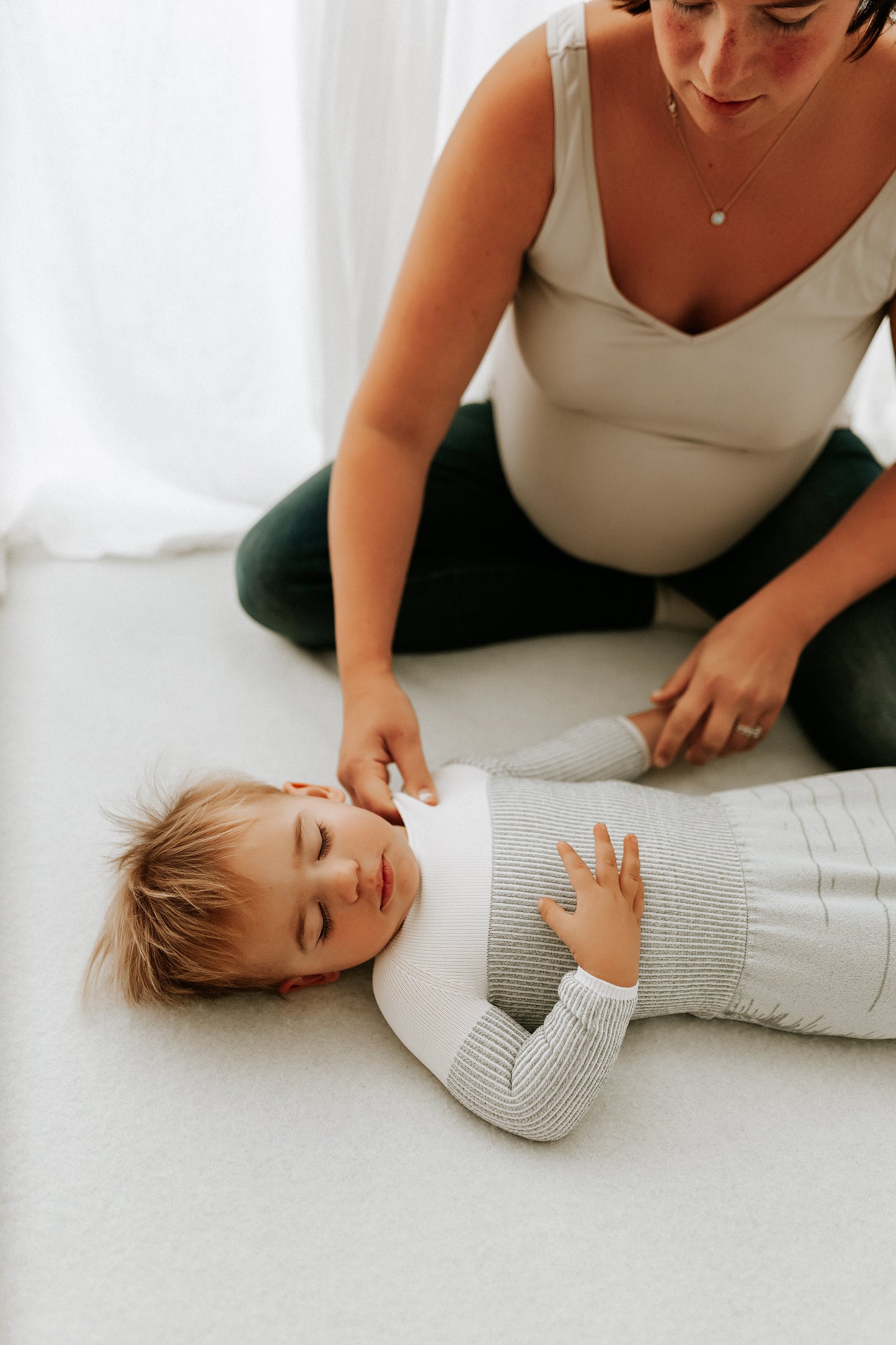 A pregnant mother putting her toddlers sleep sack on.