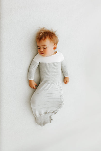 A baby sleeping in a grey transition swaddle.