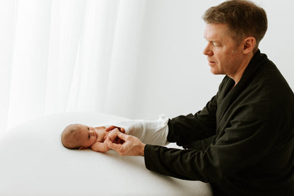 A father putting a summer sleep sack on his child.