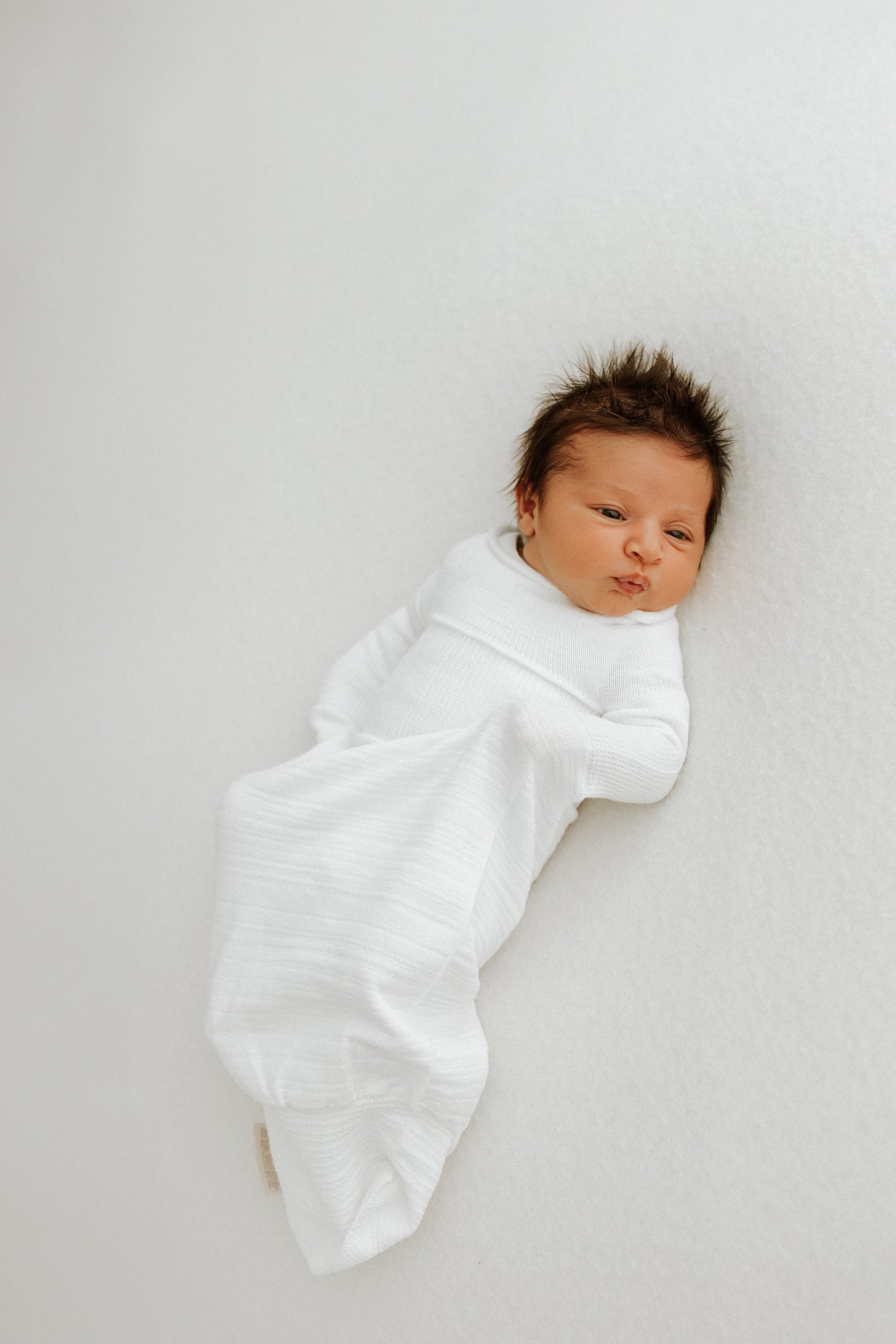 An infant resting in a swaddle sleep sack.
