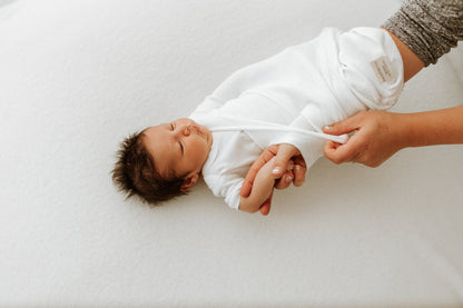 A mother putting her baby in a knit swaddle.