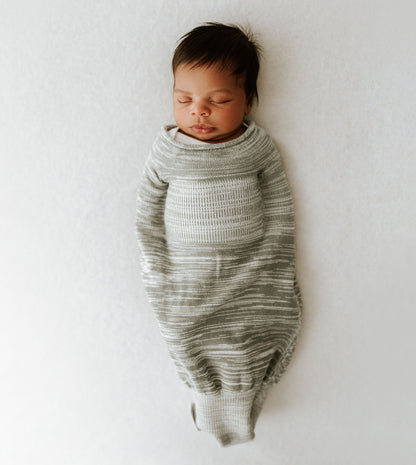 A baby sleeping in a grey swaddle.