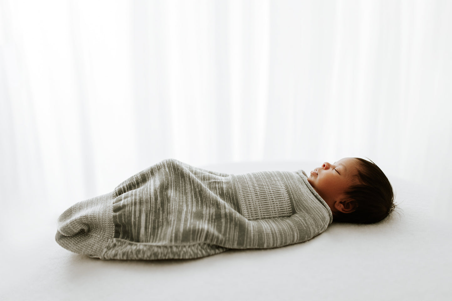 An infant sleeping in a comfortable baby swaddle.