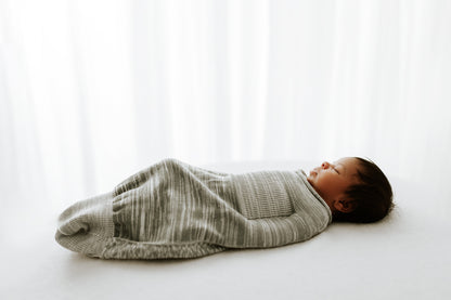 An infant sleeping in a comfortable baby swaddle.