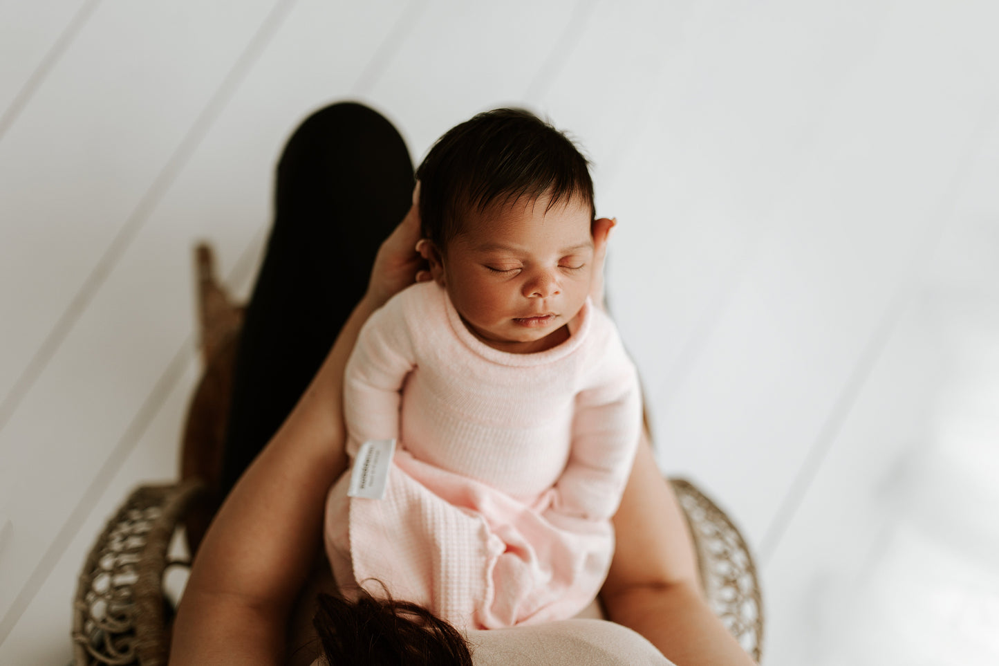A mother holding her baby in a pink sleep sack.